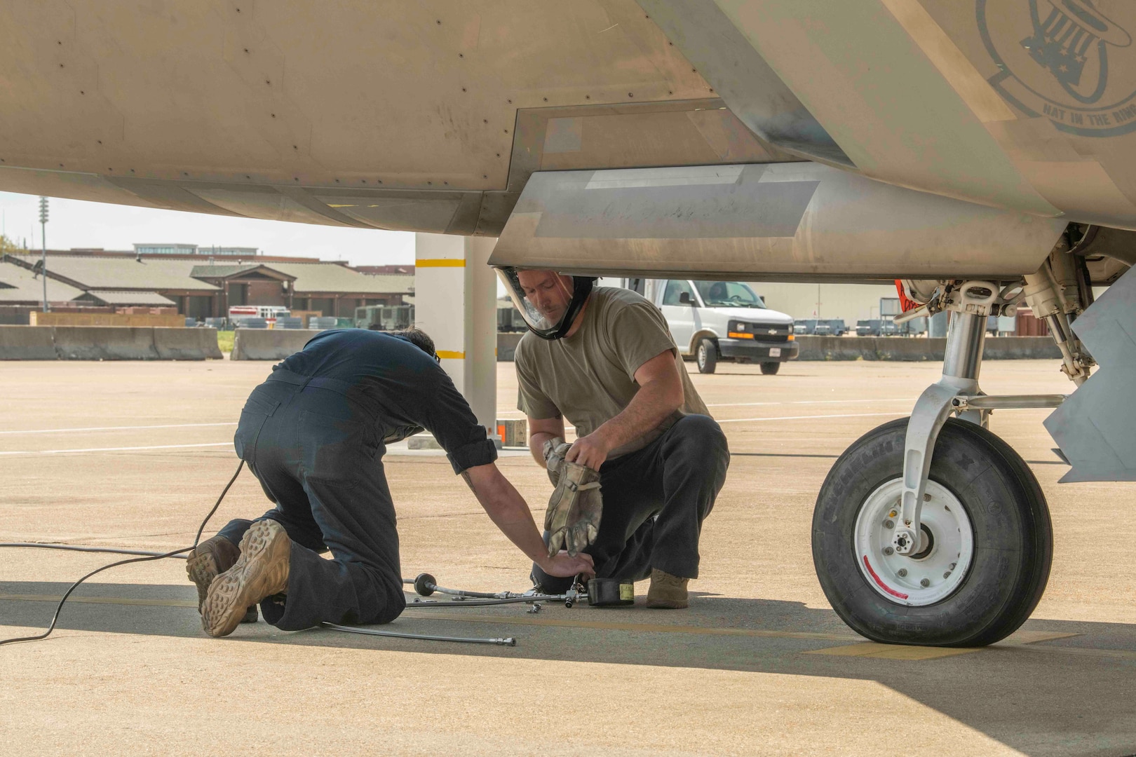 Maintenance Airmen connect a hose under an F-22 Raptor
