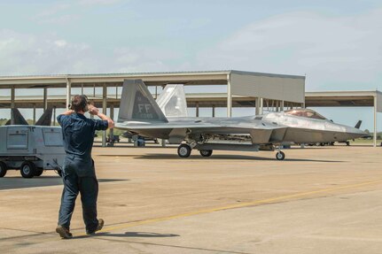 An F-22 crew chief waves the jet back in after its first flight in over one year