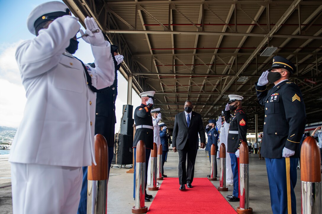 Defense Secretary Lloyd J. Austin III walks between two rows of service members.