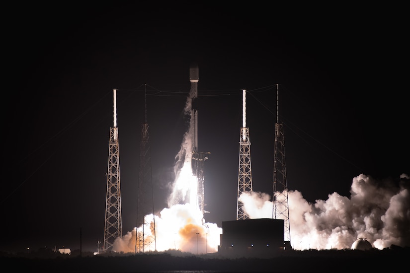 Smoke billows against the night sky as a rocket takes off.