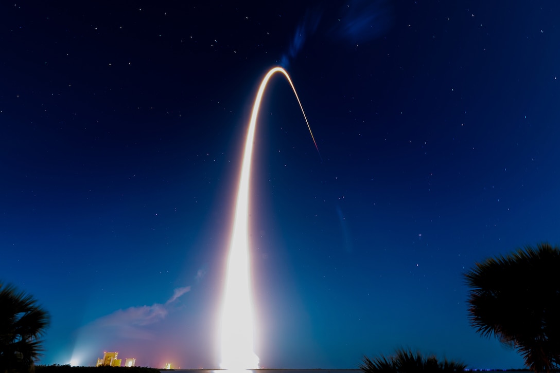 Fire from a rocket forms an arc in the night sky.