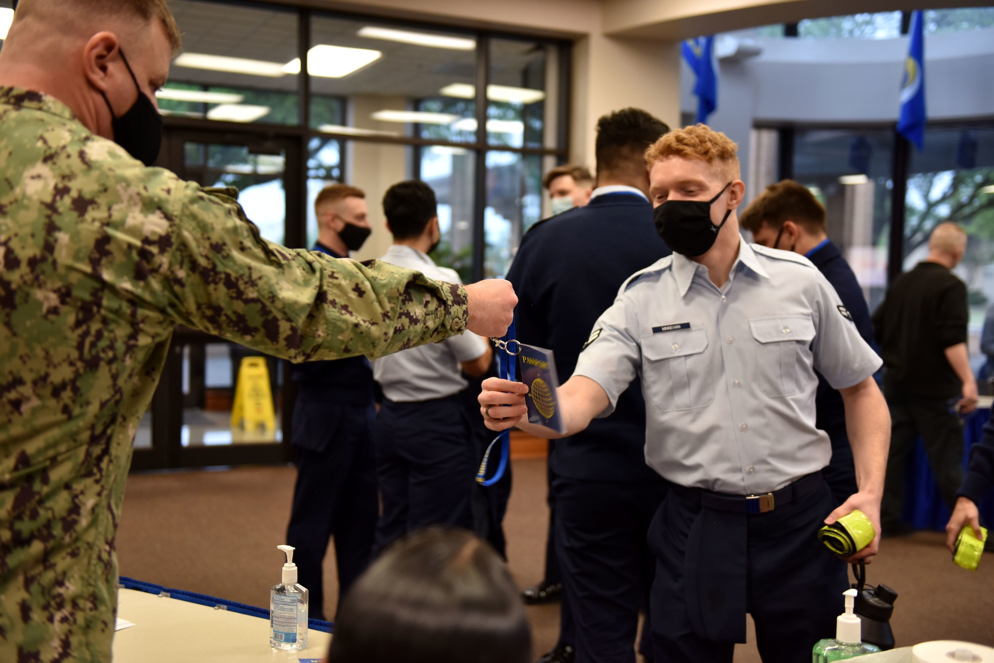 U.S. Navy Chief Petty Officer Jason Sikora, 316th Training Squadron instructor, hands Airman 1st Class Devin Minnehan, 316th TRS student, his passport during the Around the World International Cultural fair at Angelo State University in San Angelo, Texas, April 29, 2021. The passports were one of many items from the fair that students could take with them when finished touring the different culture booths. (U.S. Air Force photo by Staff Sgt. Seraiah Wolf)
