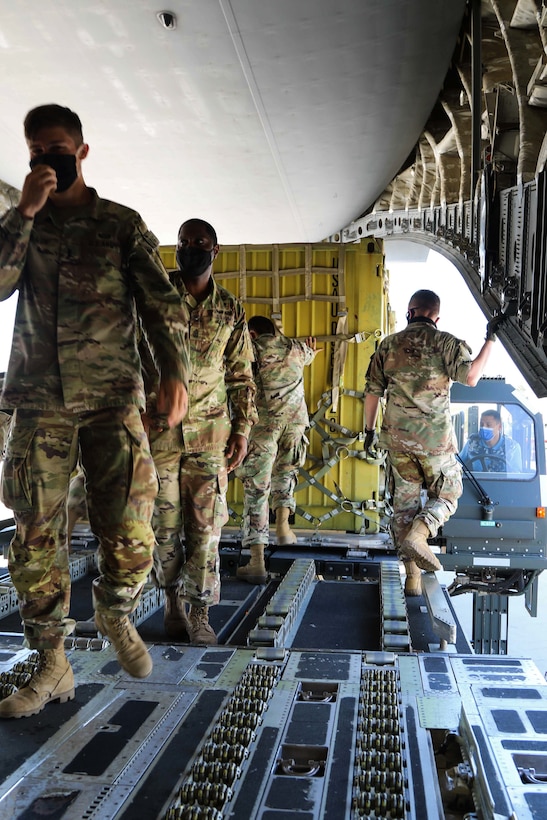 Service members in military uniforms stand inside an aircraft.