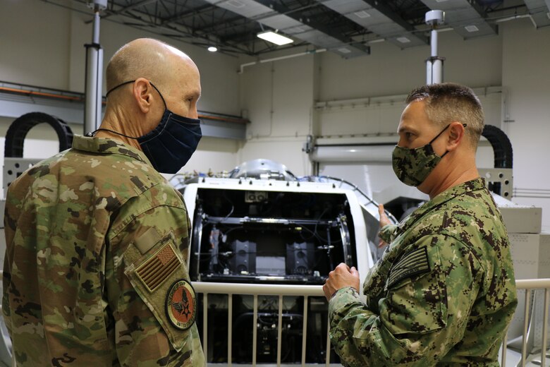 Navy Capt. Richard Folga, Department Head, Engineering and Technical Services and Program Manager of the Kraken, Naval Aerospace Medical Research Laboratory, NAMRU-Dayton and Gen. David Allvin stand on a balcony in front of the Disorientation Research Device, also known as the Kraken. The device is a one of a kind national scientific asset that provides a platform for basic science and applied research through simulation of aviation environments with customizable capsule configurations supporting one or two side by side occupants. (U.S. Navy photo/Megan Mudersbach)