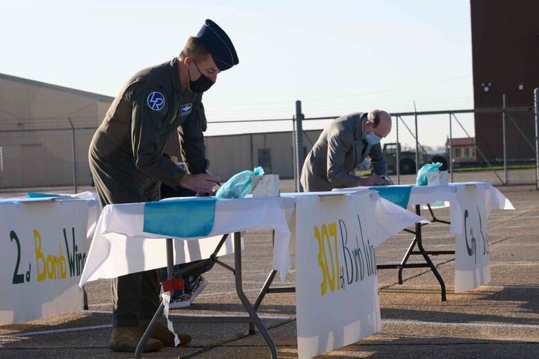 Photo of people standing at a table signing a document.