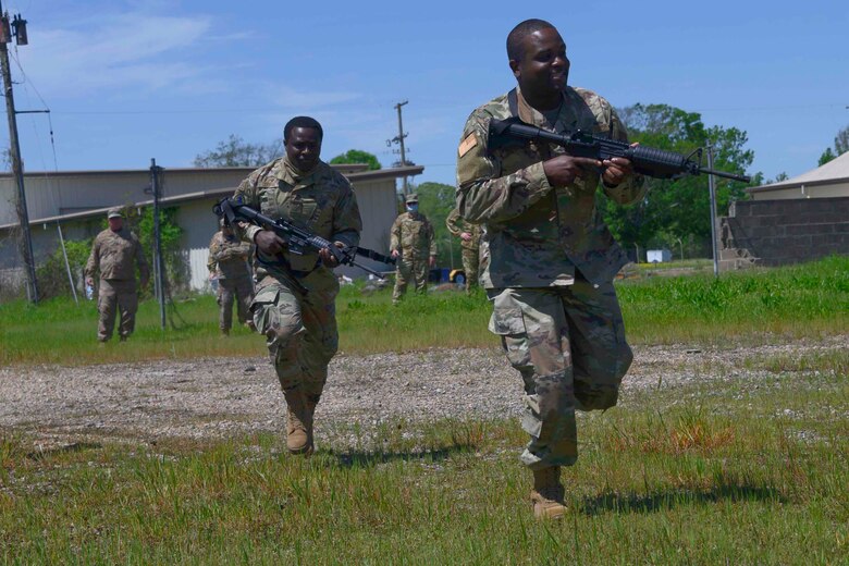 Photo of two Airmen running across a field with rifles.