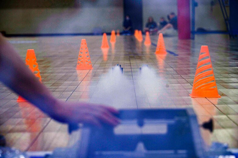 Photo of model cars taking off across a gym floor.