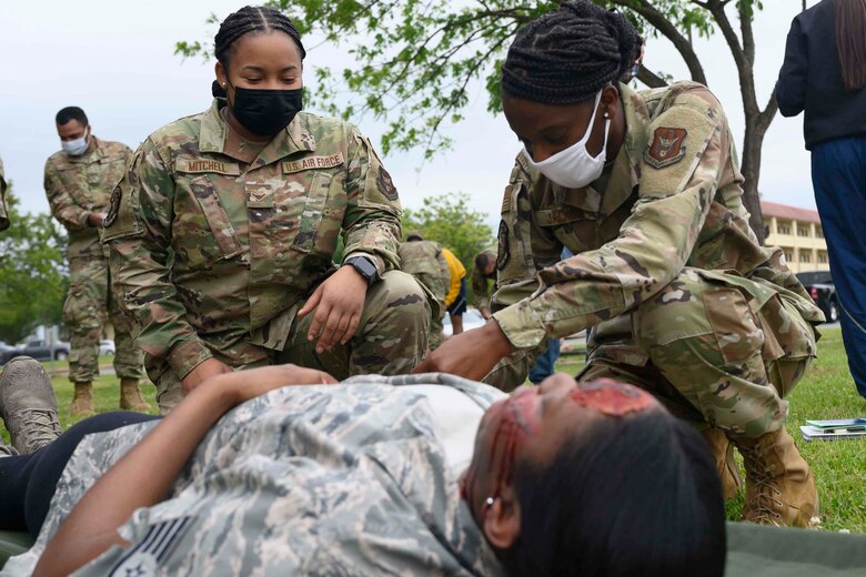Photo of two Airmen taking care of a simulated patient on a stretcher.