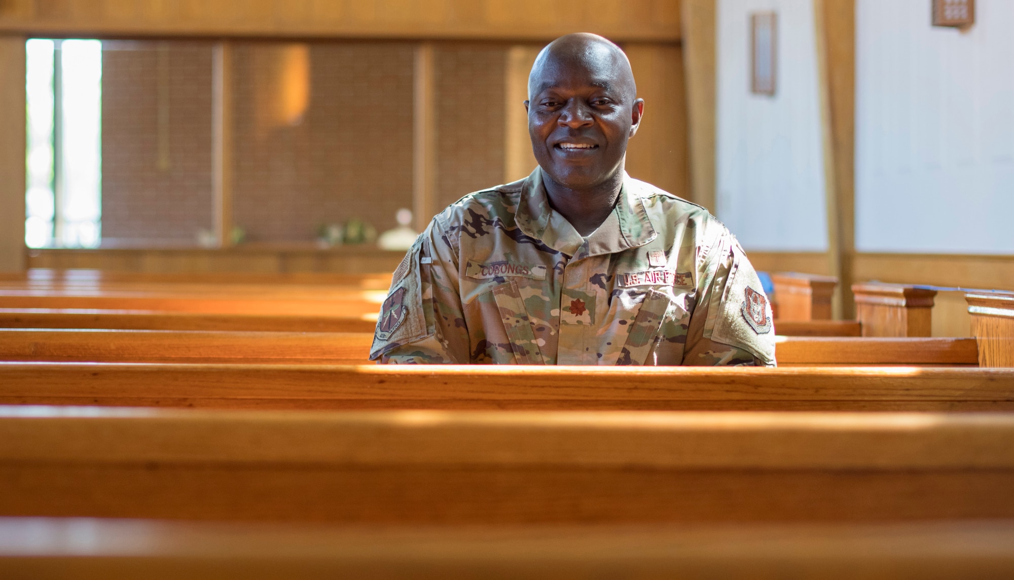 Chaplain (Maj.) Bitrus Cobongs, head chaplain for the 403rd Wing at Keesler Air Force Base, Miss., sits on a pew in Keesler's Triangle Chapel April 11, 2021. Cobongs's life began over 6,000 miles away in Nigeria where his early aspirations consisted of being a youth minister, but through closed and opened doors, he ended up serving in the U.S. military. (U.S. Air Force photo by Staff Sgt. Kristen Pittman)