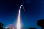 Fire from a rocket forms an arc in the night sky.