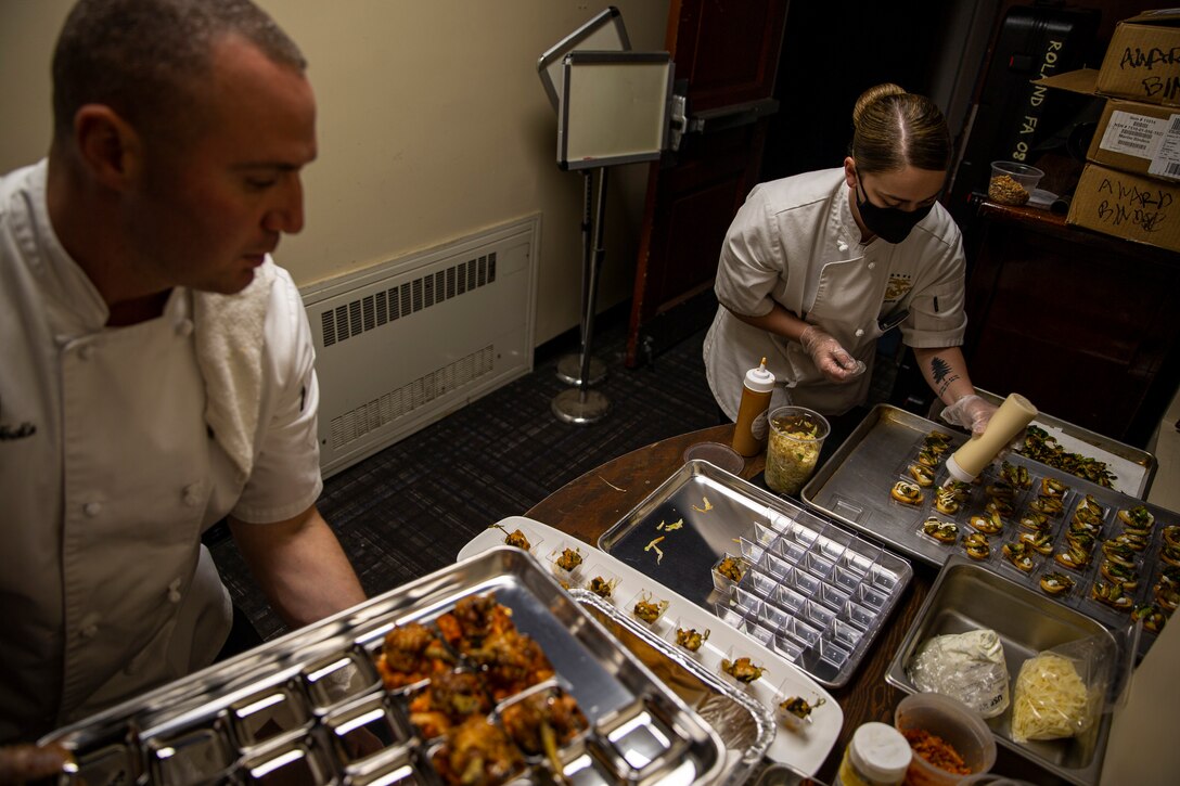 Staff Sgt. Jordan Prunty prepares food during a reception before the Friday Evening Parade at Marine Barracks Washington, D.C., April 30, 2021.