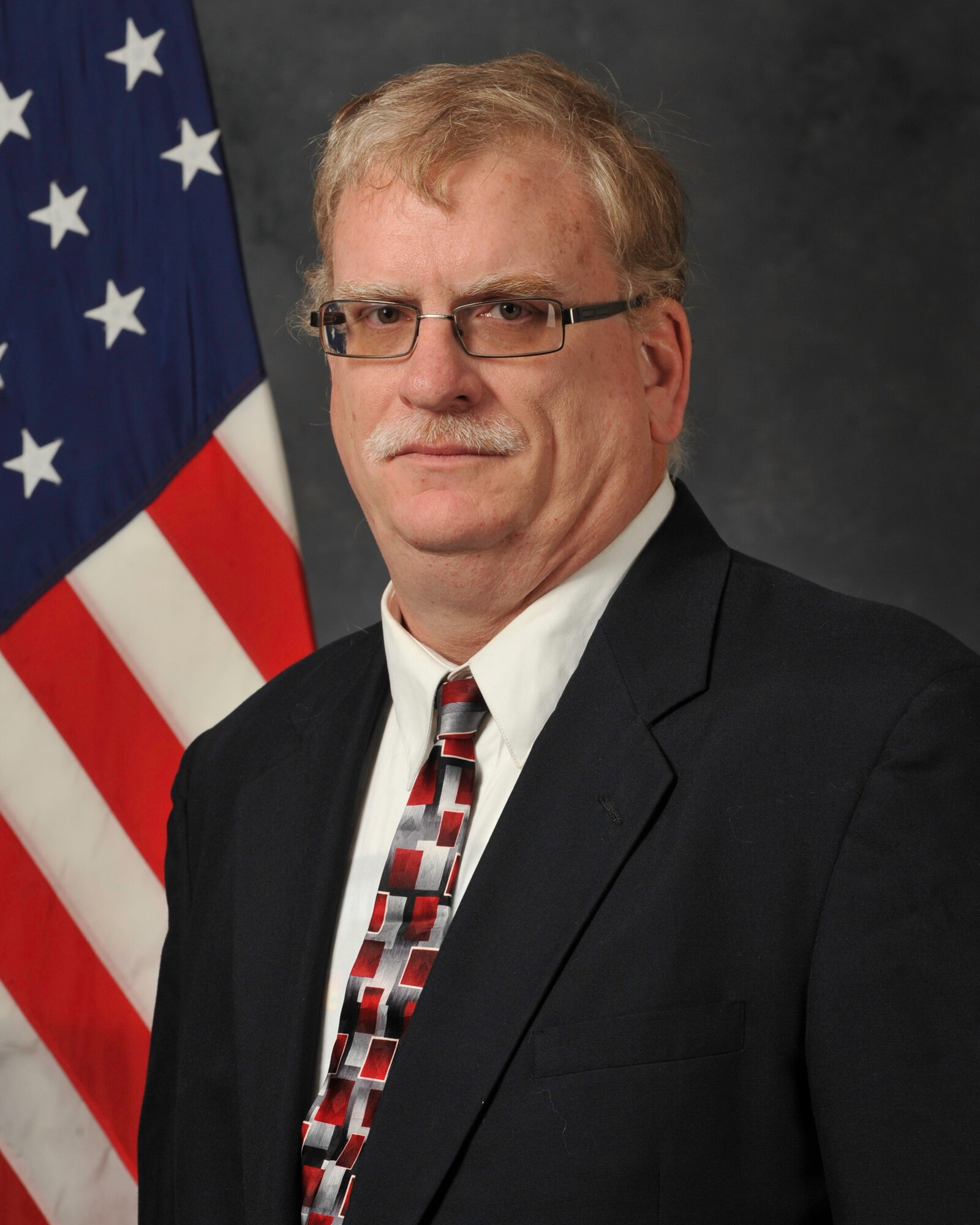 Tom Penders, 45th Civil Engineer Squadron cultural resources manager, stands in front of an American flag