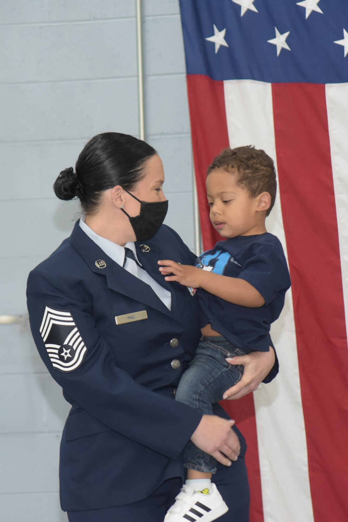 A women in Air Force Dress blues holds her toddler son.
