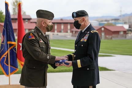 A soldier hands a flag to another soldier