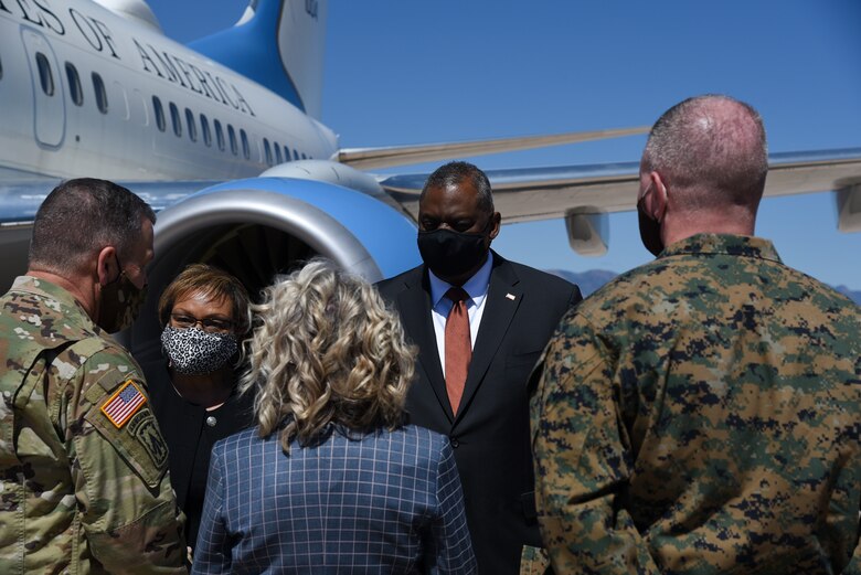 Secretary of Defense and other military personnel talk on the flight line.