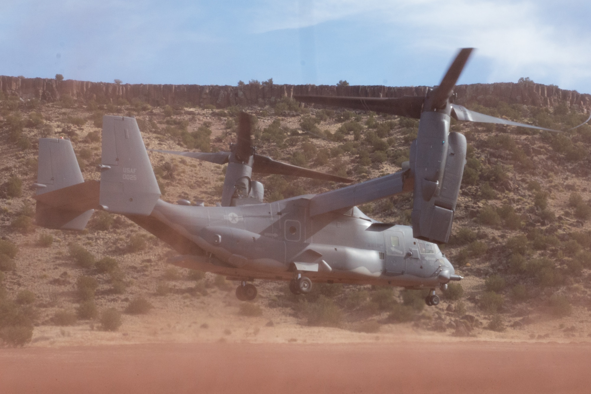 A CV-22 Takes off as red sand flies around it