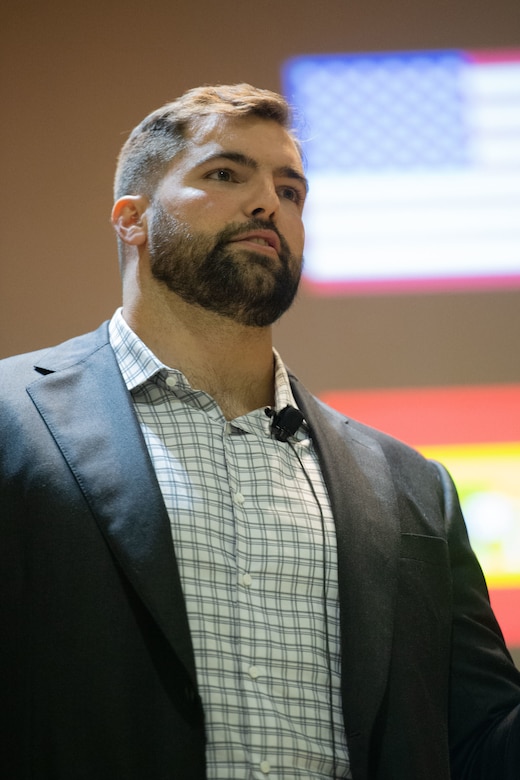 A man wearing a microphone clipped to his collar looks ahead.