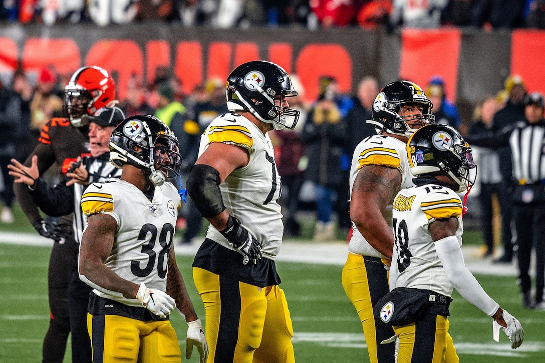 Four football players stand on a football field during a game.