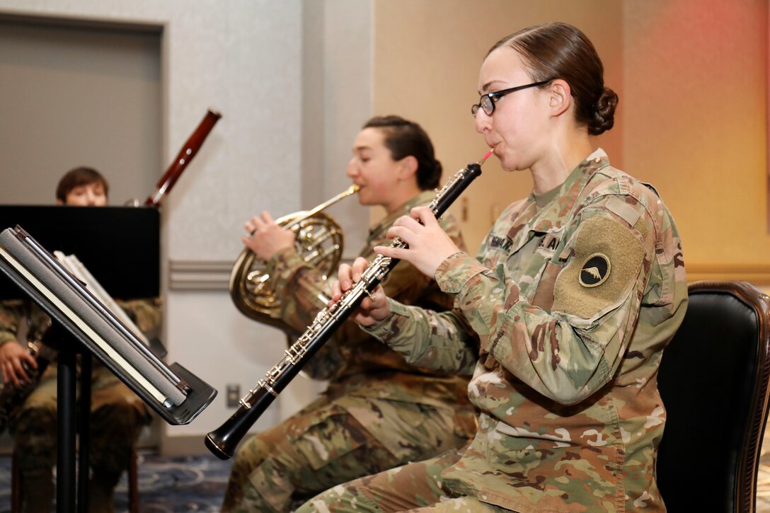 Three soldiers play musical instruments while seated.