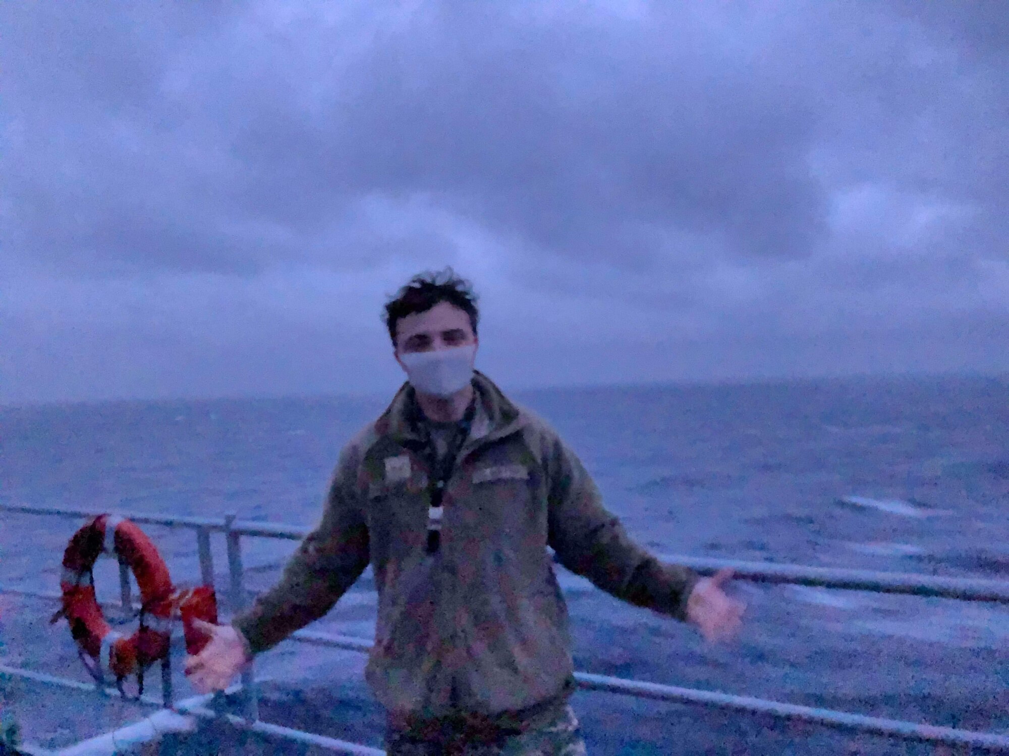 U.S. Air Force Senior Airman Alexander Garrett poses for the camera on the USS Blue Ridge (LCC-19), departing Yokosuka, Japan. The Blue Ridge is responsible for patrolling and fostering relationships within the Indo-Pacific region.  Garrett is the first intelligence analyst from the 3rd Wing to support the Blue Ridge.