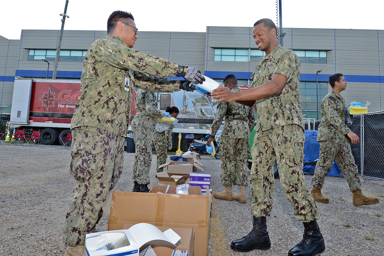 A sailor hands a box to another sailor.