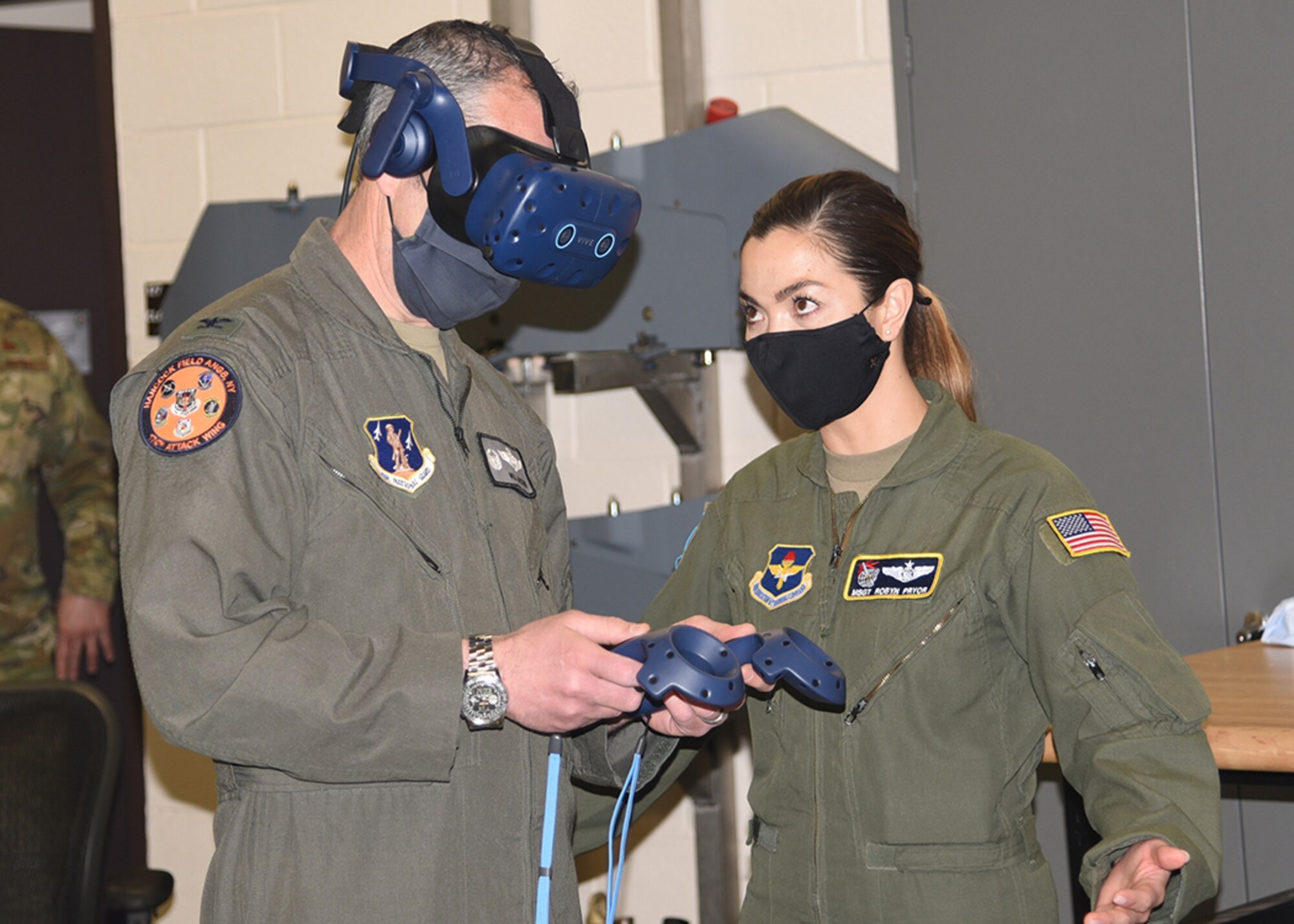 Master Sgt. Robyn Pryor., (right) from Air Education and Training Command, helps Col. William McCrink III, the commander of the 174th Attack Wing, with a demo virtual reality system. The system has two controllers with sensors, headset and a laptop with software that allows the user to explore an aircraft in different digital environments for training purposes. (U.S. Air Force photo by Master Sgt. Barbara Olney)