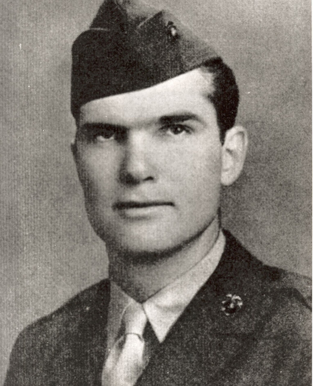 A serious looking man in a cap and uniform looks at the camera.