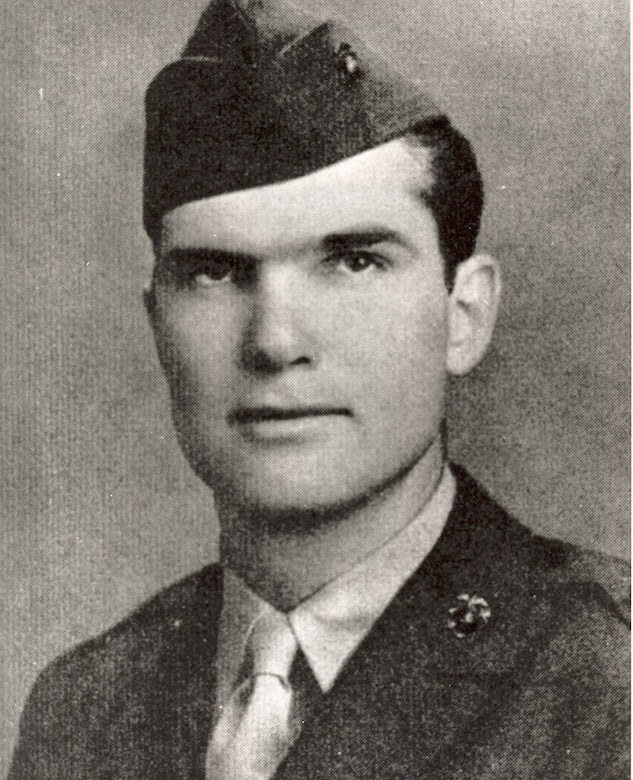 A serious looking man in a cap and uniform looks at the camera.