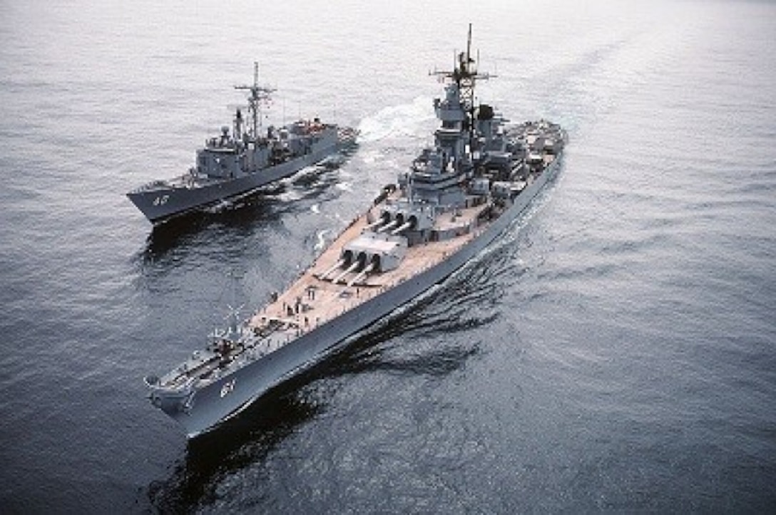 A ship sits in waters left of a much larger refueling ship.