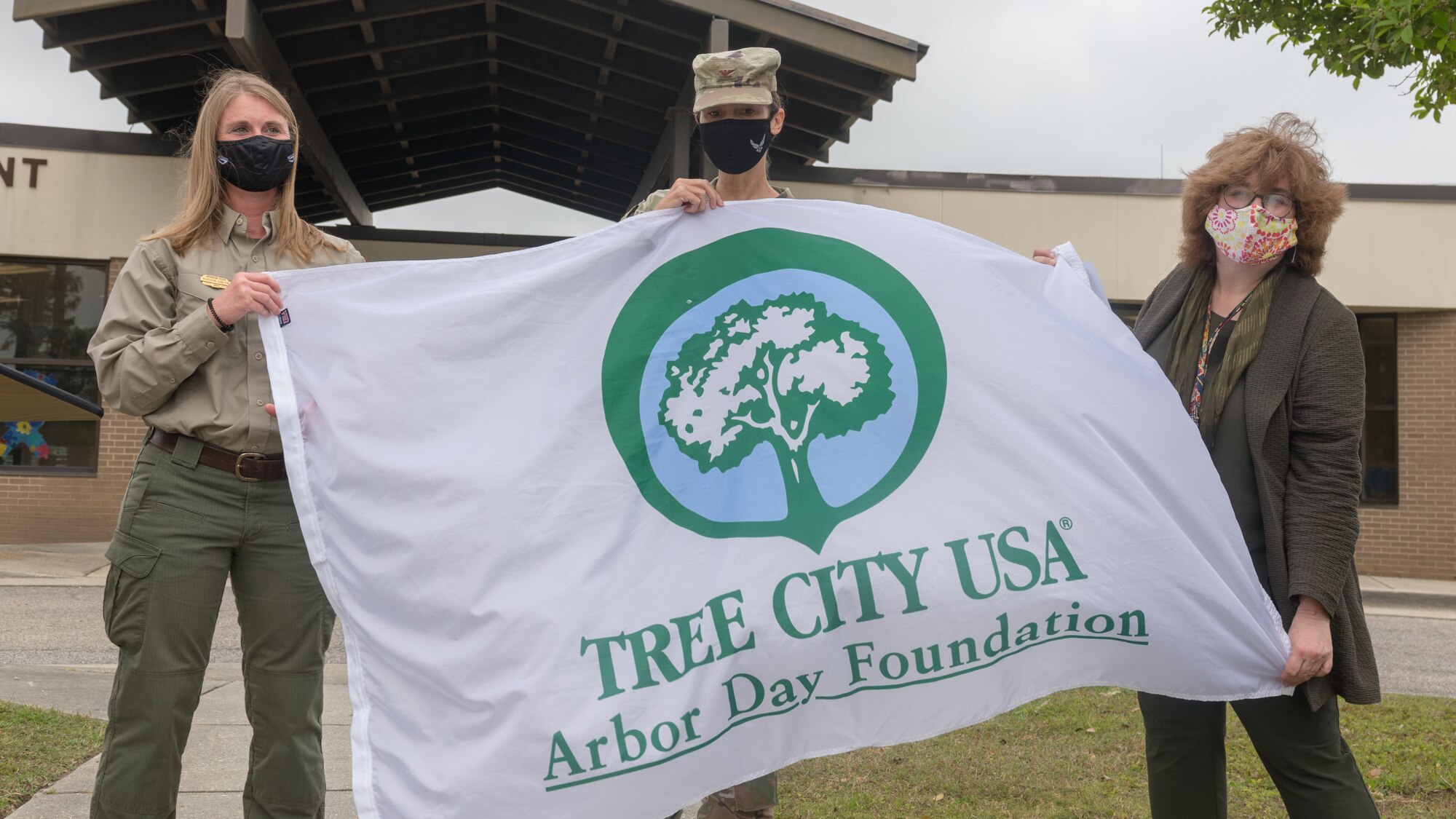 U.S. Air Force Col. Heather Blackwell, 81st Training Wing commander; Meacham Harlow, Mississippi Forestry Commission urban and community forestry partnership coordinator, and Susan Chamberlain, VECTRUS community planner, pose for a photo with the Tree City USA flag during the Arbor Day Celebration in front of the child development center at Keesler Air Force Base, Mississippi, April 30, 2021. A tree planting ceremony also took place at the event. (U.S. Air Force photo by Andre' Askew)