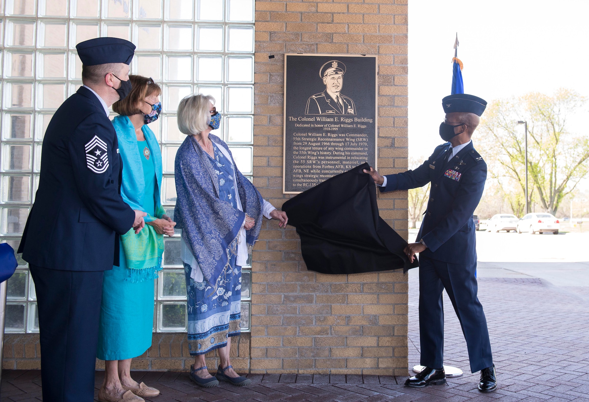 Uniformed man takes cover off of memorial plaque