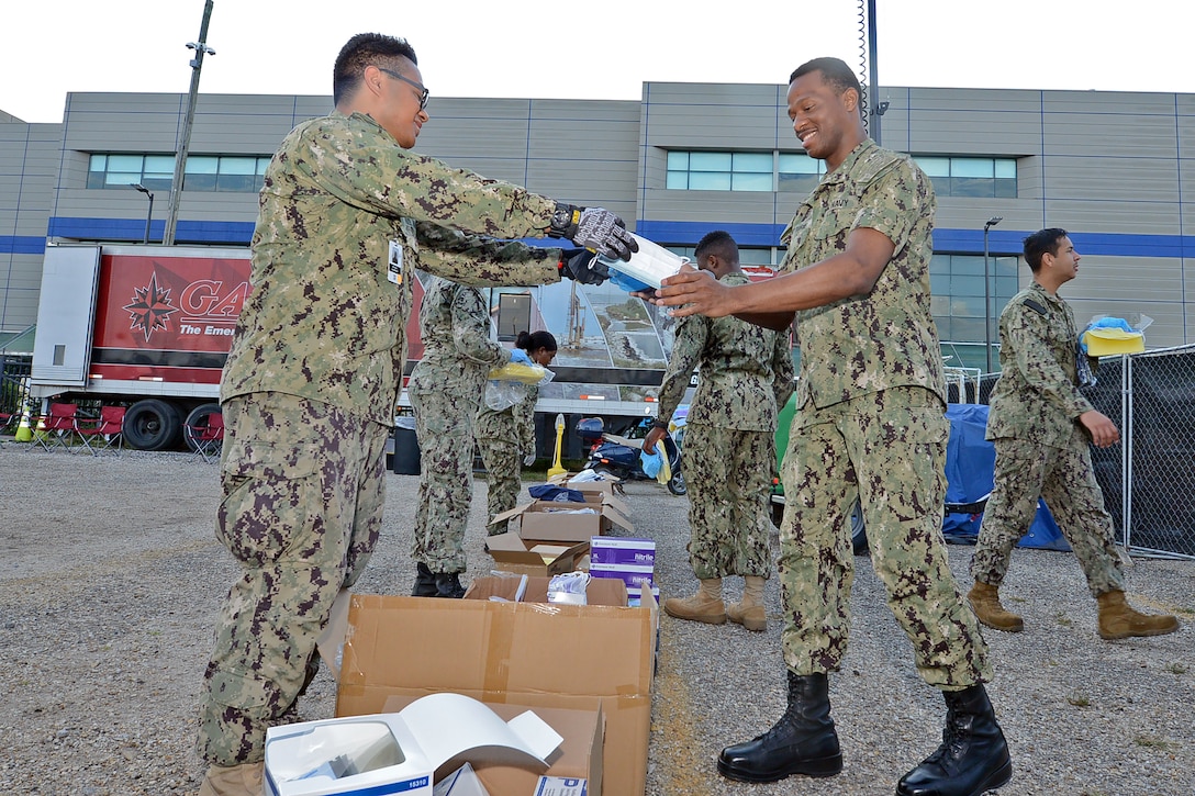 A sailor hands a box to another sailor.