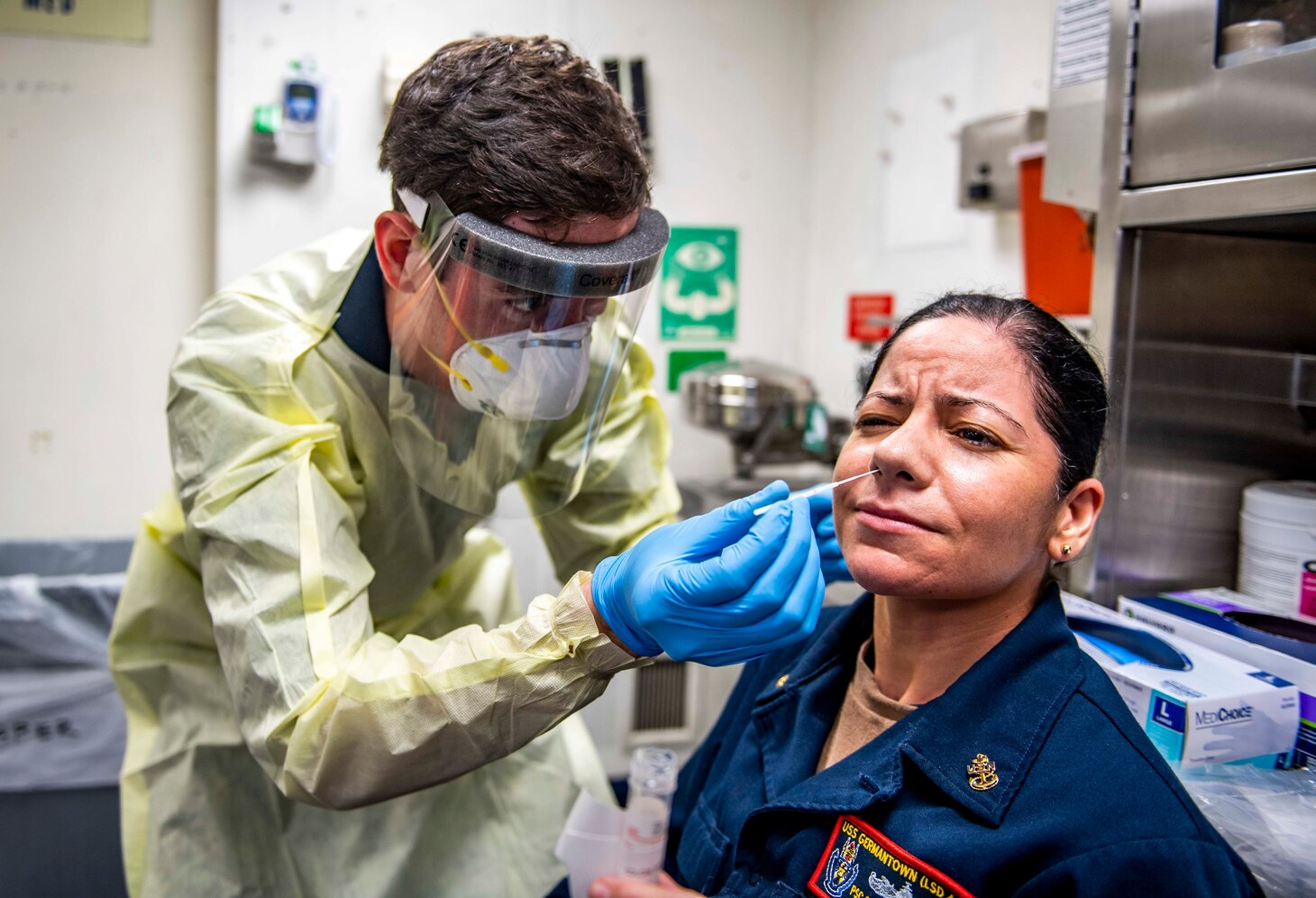 PHILIPPINE SEA (July 12, 2020) Hospital Corpsman 3rd Class Zakary Peterson, from Van, Texas, left, uses a nasal swab to conduct a COVID-19 test of Chief Personnel Specialist Melissa Colon, from Fajardo, Puerto Rico, aboard the Whidbey Island-class dock landing ship USS Germantown (LSD 42) during a complete crew screening for the virus. Germantown, part of America Expeditionary Strike Group, is operating in the 7th Fleet area of operations to enhance interoperability with allies and partners and serve as a ready response force to defend peace and stability in the Indo-Pacific region. (U.S. Navy photo by Mass Communication Specialist 2nd Class Taylor DiMartino)