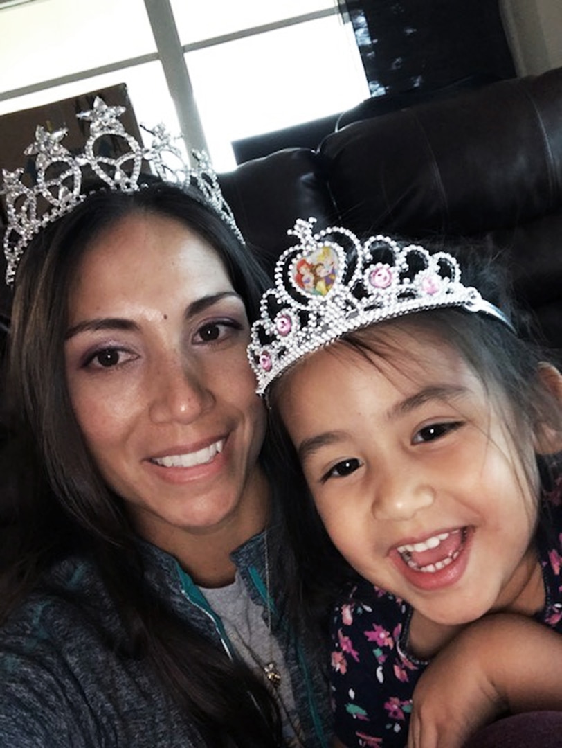 Close up photo of an Hispanic woman and young girl both wearing crowns.