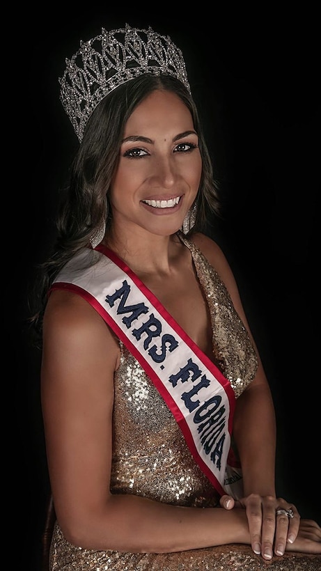 Woman wearing a crown and gold dress with a red, white and blue sash that says Mrs. Florida