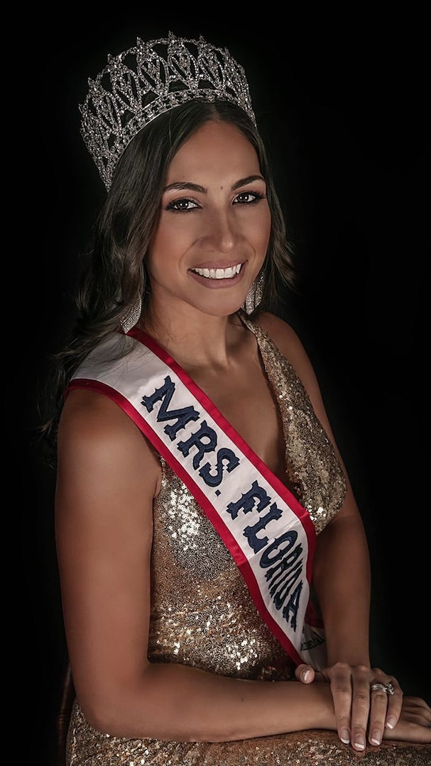 Woman wearing a crown and gold dress with a red, white and blue sash that says Mrs. Florida