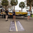 three people pose in front of a boat.