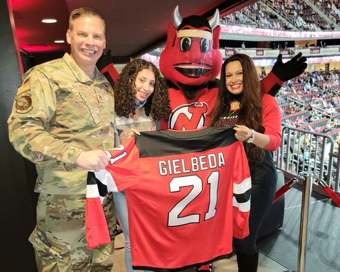 A photo of an arena with a man saluting in uniform on the jumbotron.