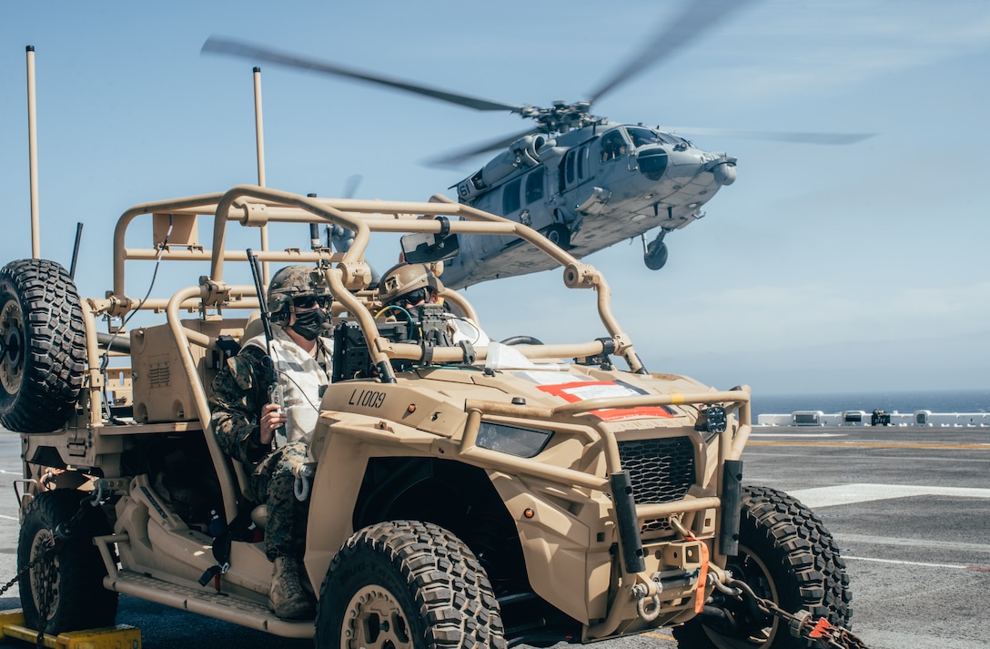 U.S. Marine Corps Sgt. Tyler Roup, left, a team leader, and Cpl. Connor Reddy, a section leader, both with Marine Medium Tiltrotor Squadron 165 (Reinforced), 11th Marine Expeditionary Unit, sit in a Light Marine Air Defense Integrated System and watch for unmanned aerial systems while an MH-60S Sea Hawk with Helicopter Sea Combat Squadron 21 takes off from the flight deck of the amphibious assault ship USS Essex (LHD 2) during a simulated strait transit, March 29. U.S. Navy and Marine Corps integration training provides the Essex Amphibious Ready Group/11th MEU its first opportunity to plan, brief, and execute multiple mission packages. Essex is underway conducting routine operations in U.S. Third Fleet.