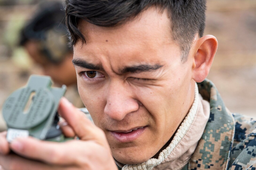 A Marine squints while looking at a compass.