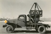 old truck with a cage and turret mounted on the flatbed.
