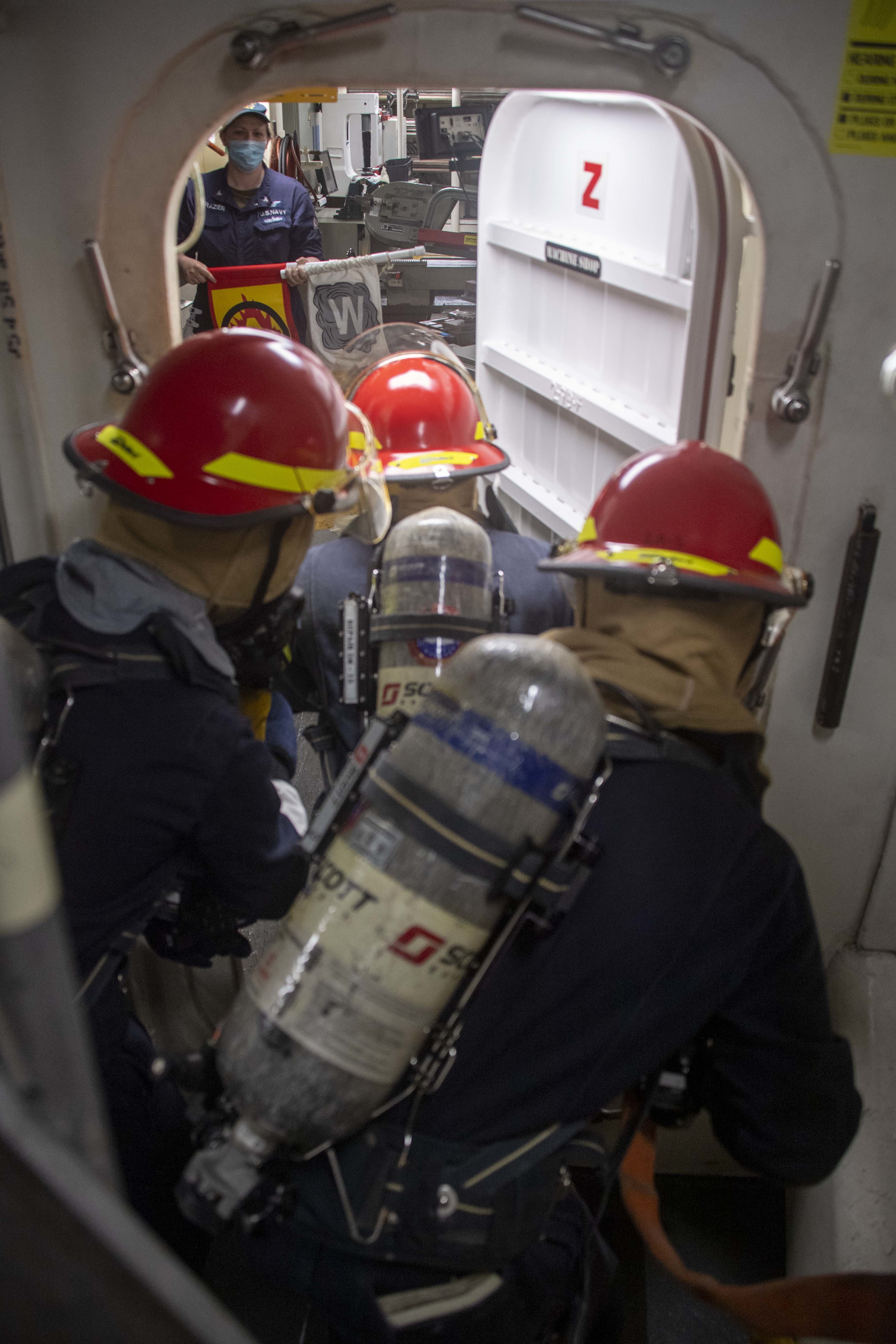 Hose team members enter a space during a simulated firefighting evolution onboard the forward-deployed amphibious assault ship USS America (LHA 6).
