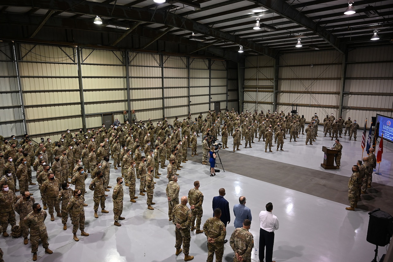 Guardsmen participate in a socially distant deployment ceremony in a hangar.