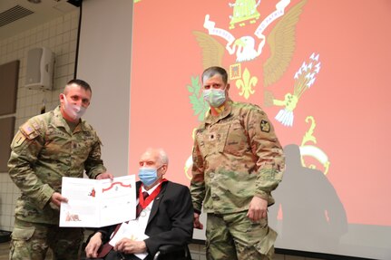 Two soldier present man with a certificate.