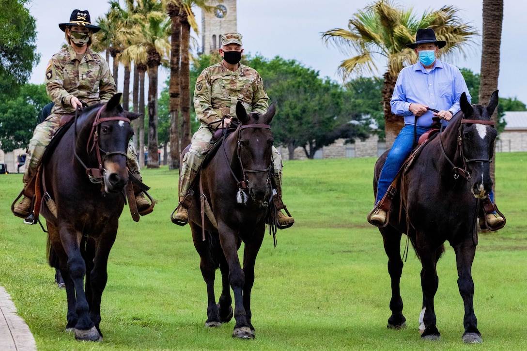 Three service members ride horses.