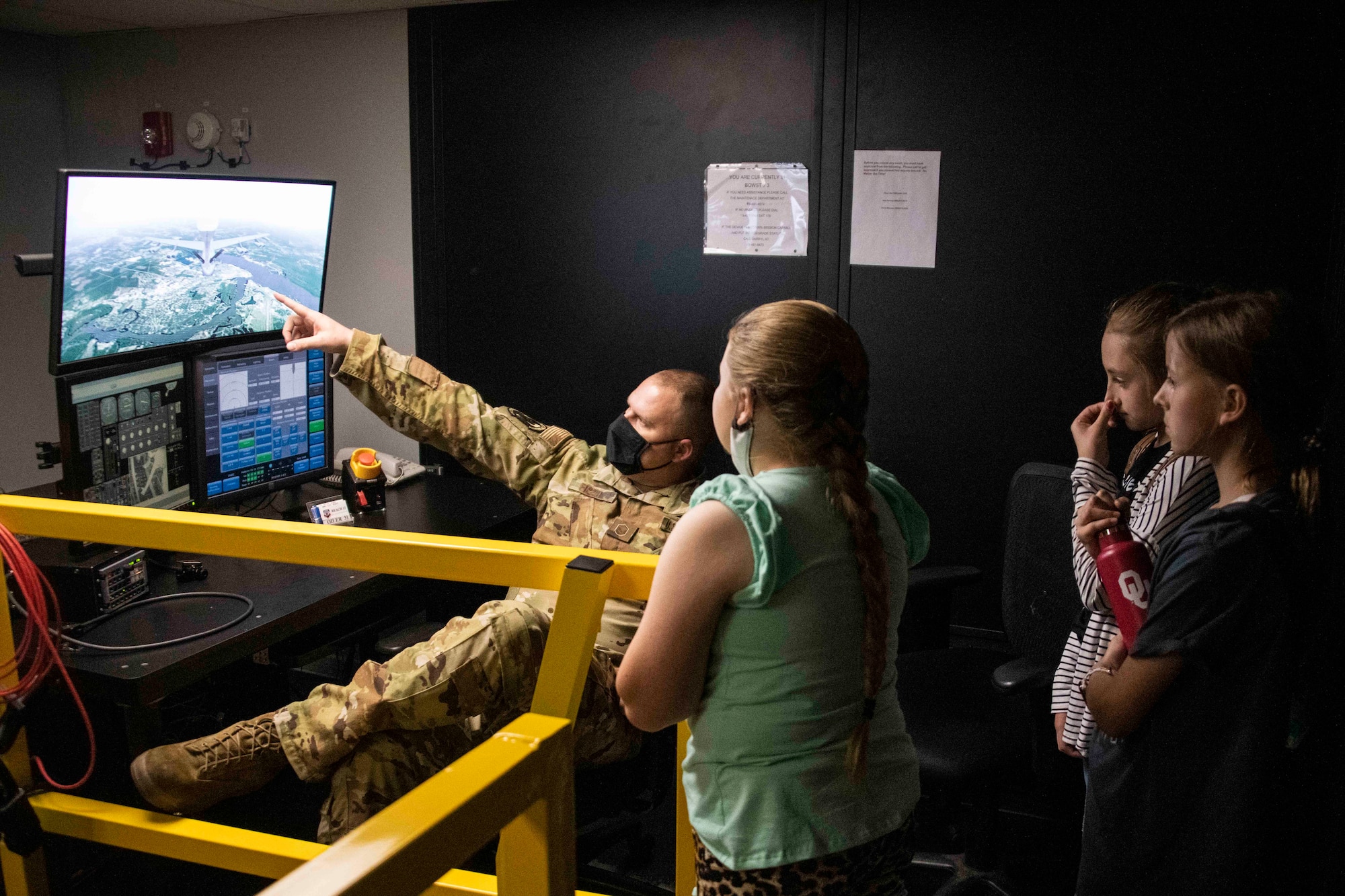 a man shows children the screen to a simulator.