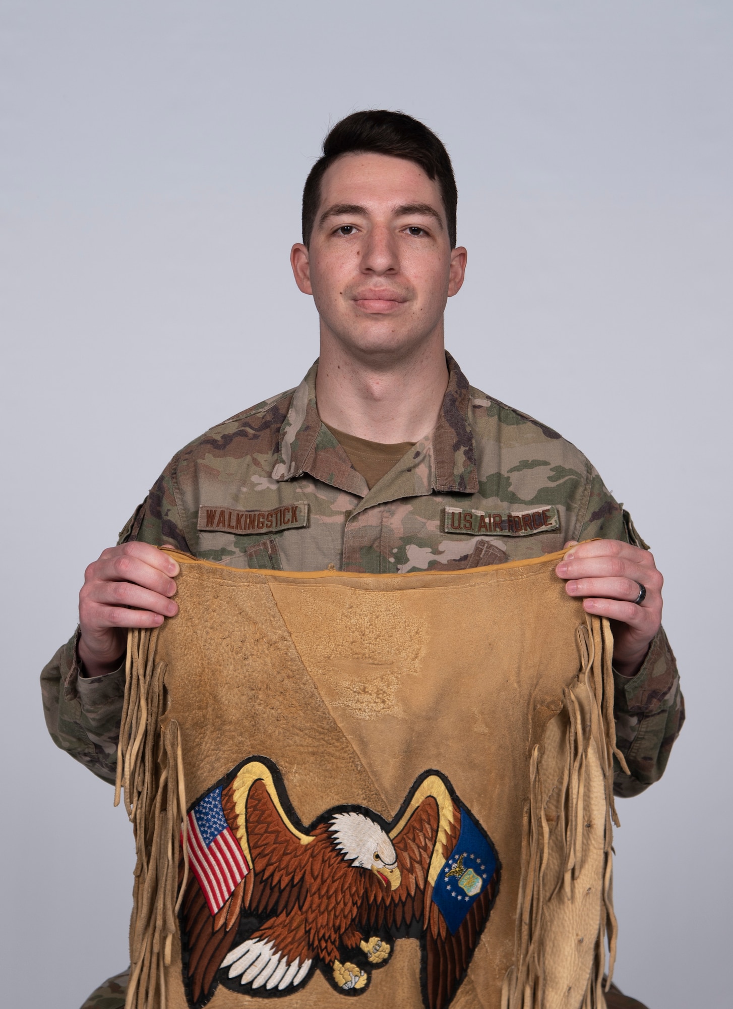 U.S. Air Force Senior Airman Taylor Walkingstick, 81st Security Forces Squadron patrolman, presents an apron for a photo at Keesler Air Force Base, Mississippi, April 29, 2021. The apron was handmade by his father, who also served in the military. (U.S. Air Force photo by Senior Airman Kimberly L. Mueller)