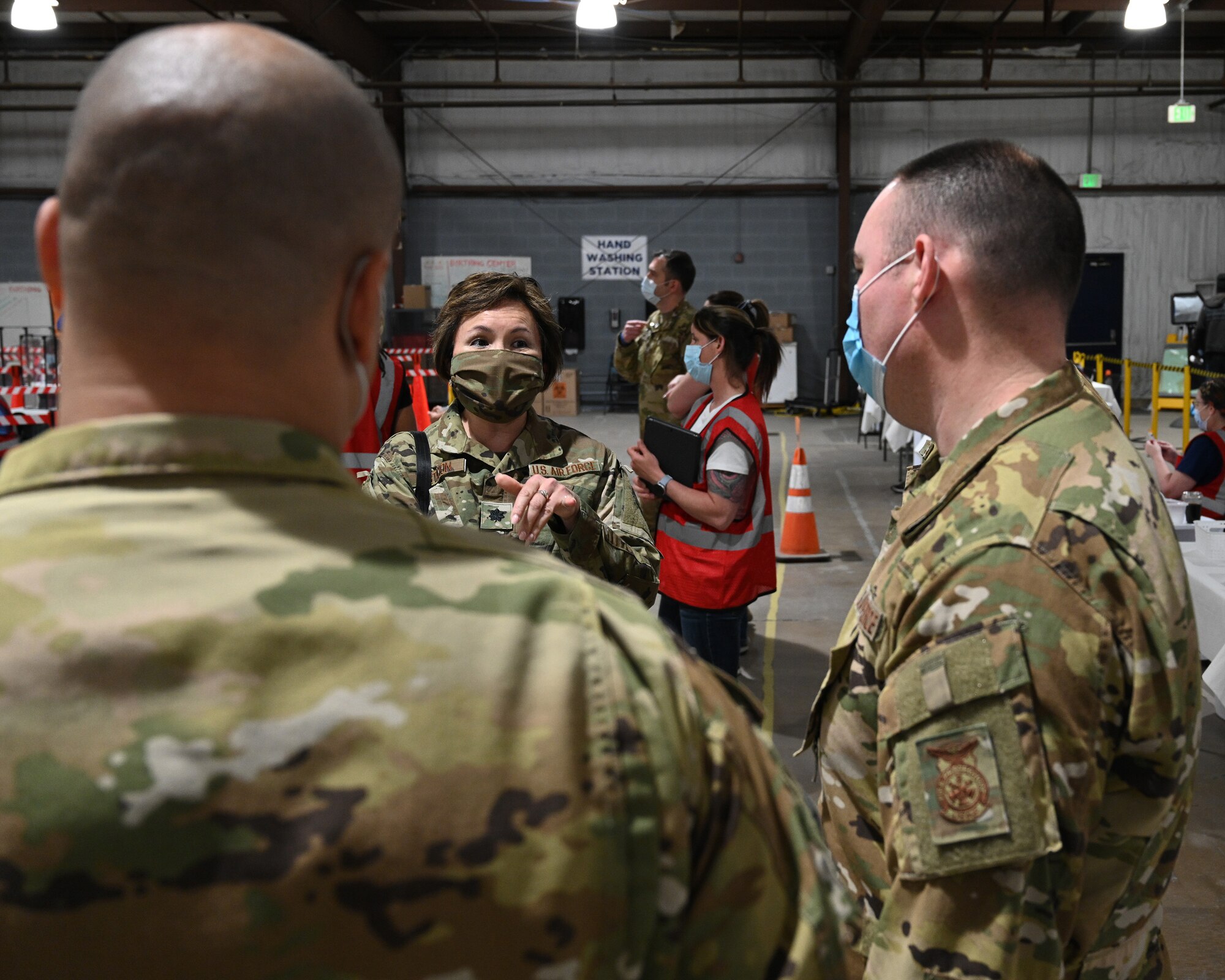U.S. Air Force Lt. Col. Christine Estacion (middle), health services administrator assigned to the 175th Medical Group, speaks with U.S. Air Force Tech. Sgt. William Blakely (right) and U.S. Air Force Master Sgt. Jason Shanley, firefighters assigned to the 175th Civil Engineer Squadron, at the COVID-19 mass vaccination site at the Maryland State Fairgrounds in Timonium, Md., April 15, 2021.