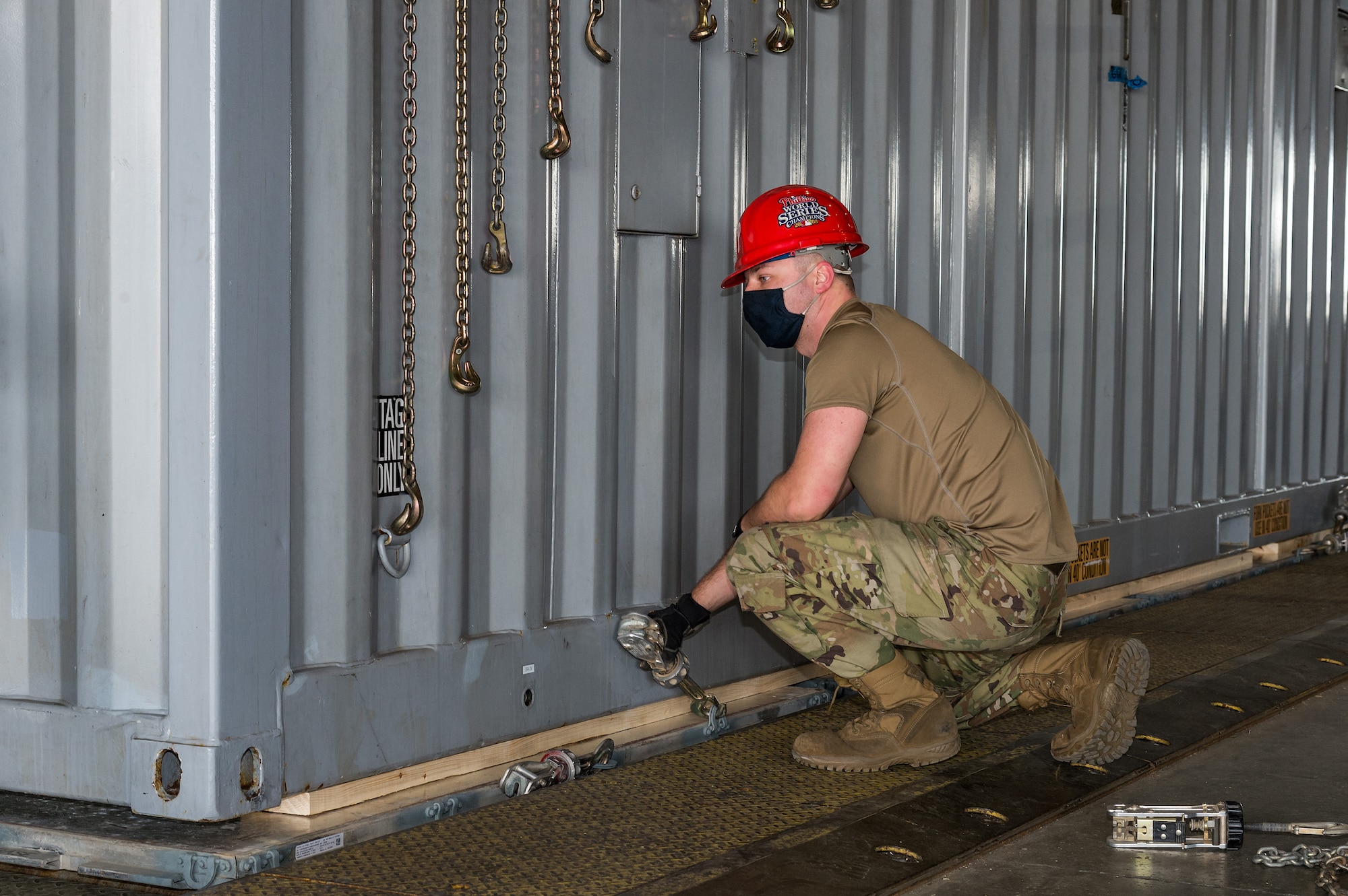 Senior Airman Matthew Rahm, 436th Aerial Port Squadron outsized cargo processor, aligns a tie-down device with cargo chains at Dover Air Force Base, Delaware, April 22, 2021. The 436th APS's primary mission is to provide airlift support for the movement of cargo, mail and passengers to support global operations. (U.S. Air Force photo by Roland Balik)