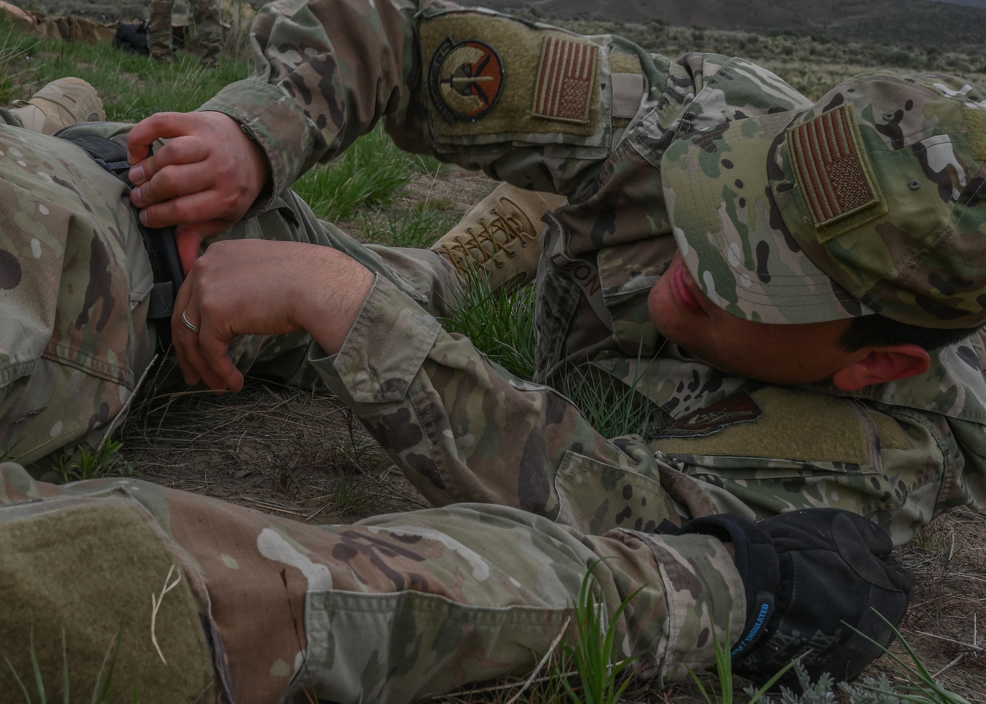 A U.S. Air Force tactical air control party Airman with the 5th Air Support Operations Squadron applies a tourniquet to his wingman at Yakima Training Center, Washington, April 28, 2021. During the week-long field training exercise, TACP Airmen conducted various medical practices in order to meet changing tactical requirements and advance ground skill sets for varying mission requirements. (U.S. Air Force photo by Airman 1st Class Callie Norton)